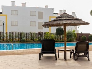 A poolside area with two lounge chairs and a thatched umbrella. - Apartment with air conditioning - 6 guests (Tavira)