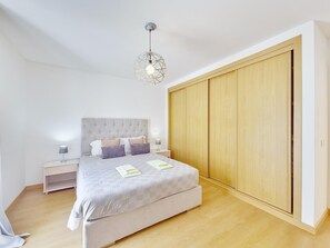 A bedroom with a bed, nightstands, a wardrobe, and a hanging light fixture. - Central apartment, AC - 4 guests (Tavira)