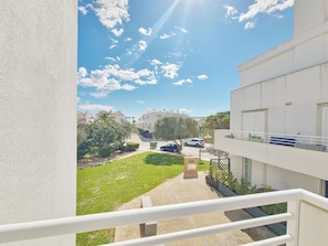 A residential building with a balcony, a paved courtyard, and a clear sky. - Central apartment, AC - 4 guests (Tavira)