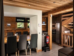 A modern kitchen with wooden accents, a dining area with a table and chairs, and a staircase with a wooden railing. - Chalet pets welcome - 8 guests, mountain view (La Clusaz)