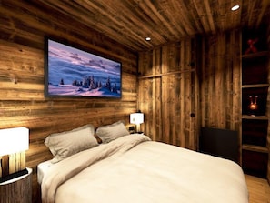 A bedroom with a wooden wall, a bed, a mounted TV, and a shelf with a decorative item. - Central duplex, mountain view - 4 guests (Val-d'Isère)
