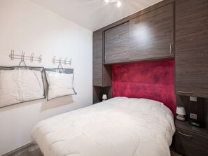 A bedroom with a bed, a wardrobe, a bedside table, and a wall-mounted light fixture. - Charming studio mountain view - 4 guests (Saint-Lary-Soulan)