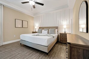 A bedroom with a bed, bedside tables, a ceiling fan, and a large mirror. - New 5BR Reunion Villa, Themed Rooms, Resort Pools (Kissimmee)