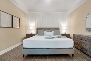 A bedroom with a large bed, two bedside tables, a dresser, and a mirror. - New 5BR Reunion Villa, Themed Rooms, Resort Pools (Kissimmee)