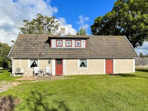 A single-story house with a tiled roof, a red door, and a small porch with two chairs. - 4 Person Holiday Home in Kopingsvik (Kopingsvik)