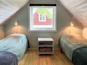 A small, cozy room with two beds, a window with a view of a red building, and a shelf with folded items. - 4 Person Holiday Home in Kopingsvik (Kopingsvik)