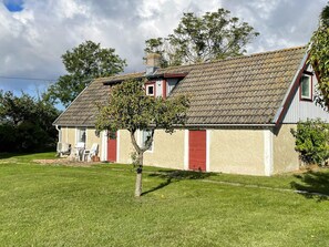A single-story house with a sloped roof, a small porch with outdoor furniture, and a well-maintained lawn. - 4 Person Holiday Home in Kopingsvik (Kopingsvik)