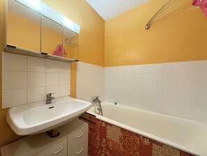 A bathroom with a white sink, a mirror, a white bathtub, and a towel rack. - Cozy studio with forest view - 4 guests (Les Orres)