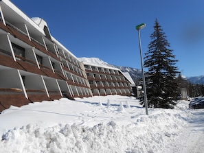 A modern building with a sloped roof, surrounded by snow and a clear blue sky. - Cozy studio, south balcony, 4 guests (Saint-Chaffrey)