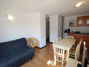A compact living space with a sofa, dining table, chairs, a kitchen area with a microwave, and a wooden cabinet. - Apartment pets allowed, 7 guests, piste view (Villarodin-Bourget)