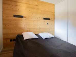 A single bed with a black mattress and two white pillows in a room with wooden panel walls. - Apartment pets allowed, 7 guests, piste view (Villarodin-Bourget)