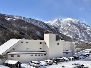 A modern building with a parking lot full of cars, surrounded by snow-covered mountains. - Cozy studio with south-facing balcony - 4 guests (Saint-Chaffrey)