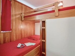 A bunk bed with a red polka dot bedspread, a wooden headboard, and a window with a red curtain. - Studio with south-facing balcony - 4 guests (Saint-Chaffrey)