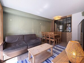 A compact living space with a sofa, dining table, chairs, a small wooden table, and a lamp. - Renovated apartment in Les Orres - 6 guests (Les Orres)