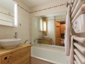 A bathroom with a bathtub, a wooden vanity with a sink, and a mirror. - Studio, parking, pets welcome - 3 guests (La Salle-les-Alpes)