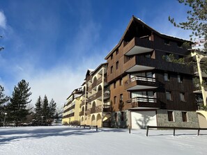 A multi-story hotel with balconies, a snow-covered ground, and a clear sky. - Pleasant studio, parking - mountain view (La Salle-les-Alpes)