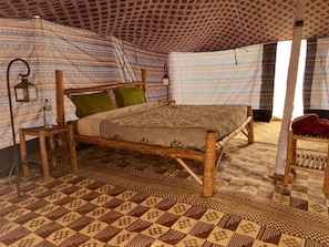 A tent with a bed, patterned curtains, and a checkered floor. - Camp Rêve de Nomade (Lompoul)