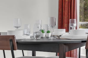 A dining table set with white plates, clear glasses, and cutlery, with a small potted plant on the table. - Luxury South Kensington Retreat (London)