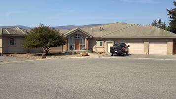 A residential property with a garage, a driveway, and a tree in the foreground.
