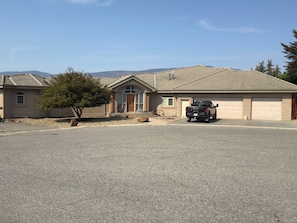 A residential property with a garage, a driveway, and a tree in the foreground. - Spacious 3BR Knox Mountain Home | 5 Min to Downtown (Kelowna)
