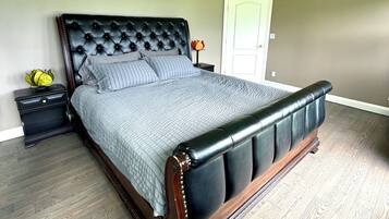 A bedroom with a large bed, a nightstand, a lamp, and a door.