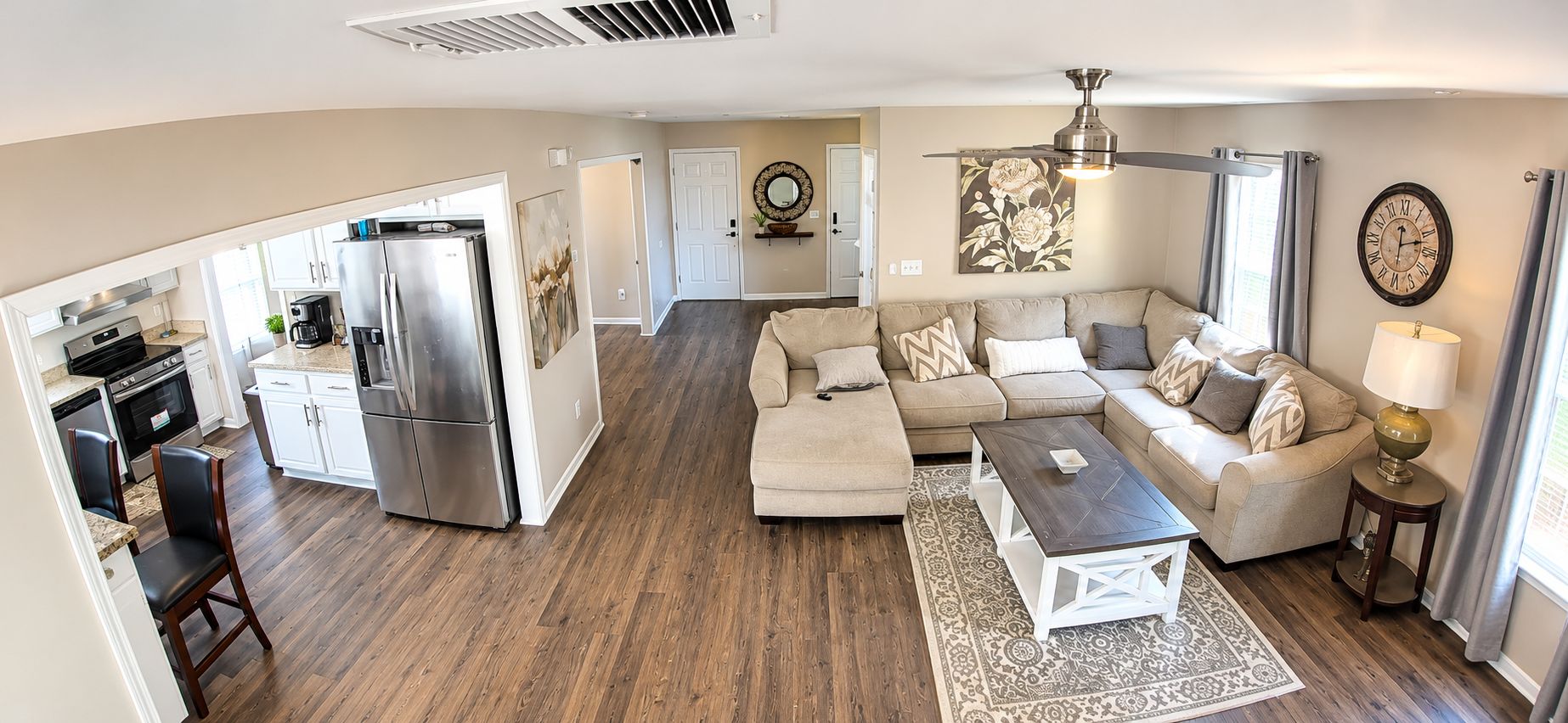 Amplia sala de estar con un conjunto de sofás, una mesa de centro y un comedor con refrigerador y electrodomésticos de cocina.