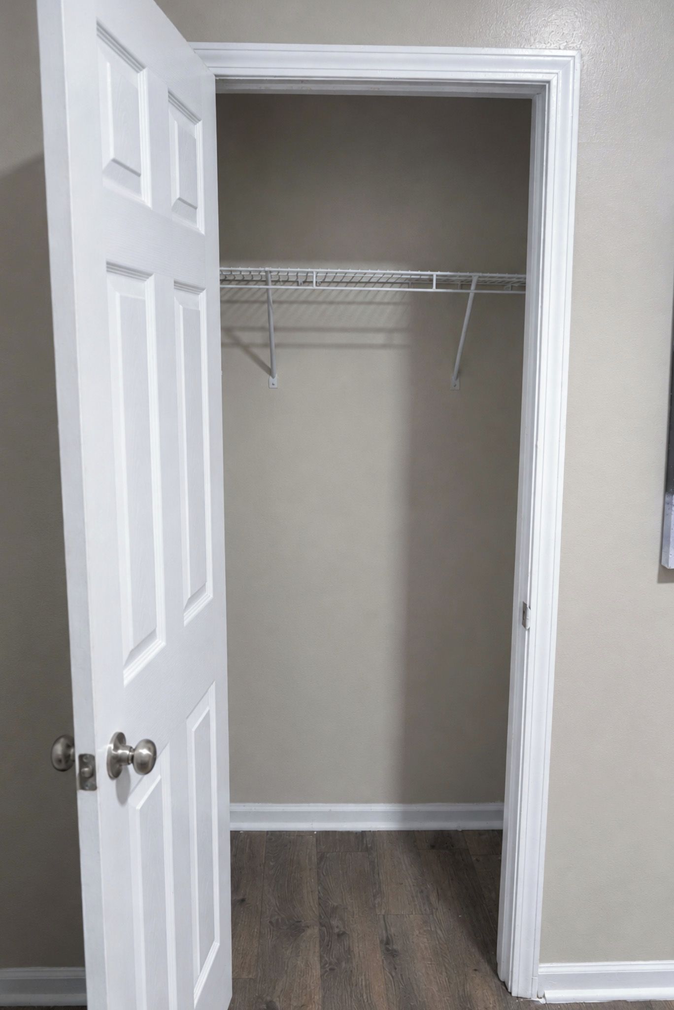 A closed door with a white frame, a wooden floor, and a beige wall.