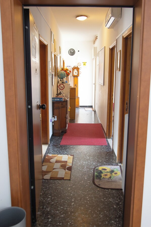 A hallway with wooden doors, a clock, and a red carpet leading to a room. - Vrbo Property (Venezia)