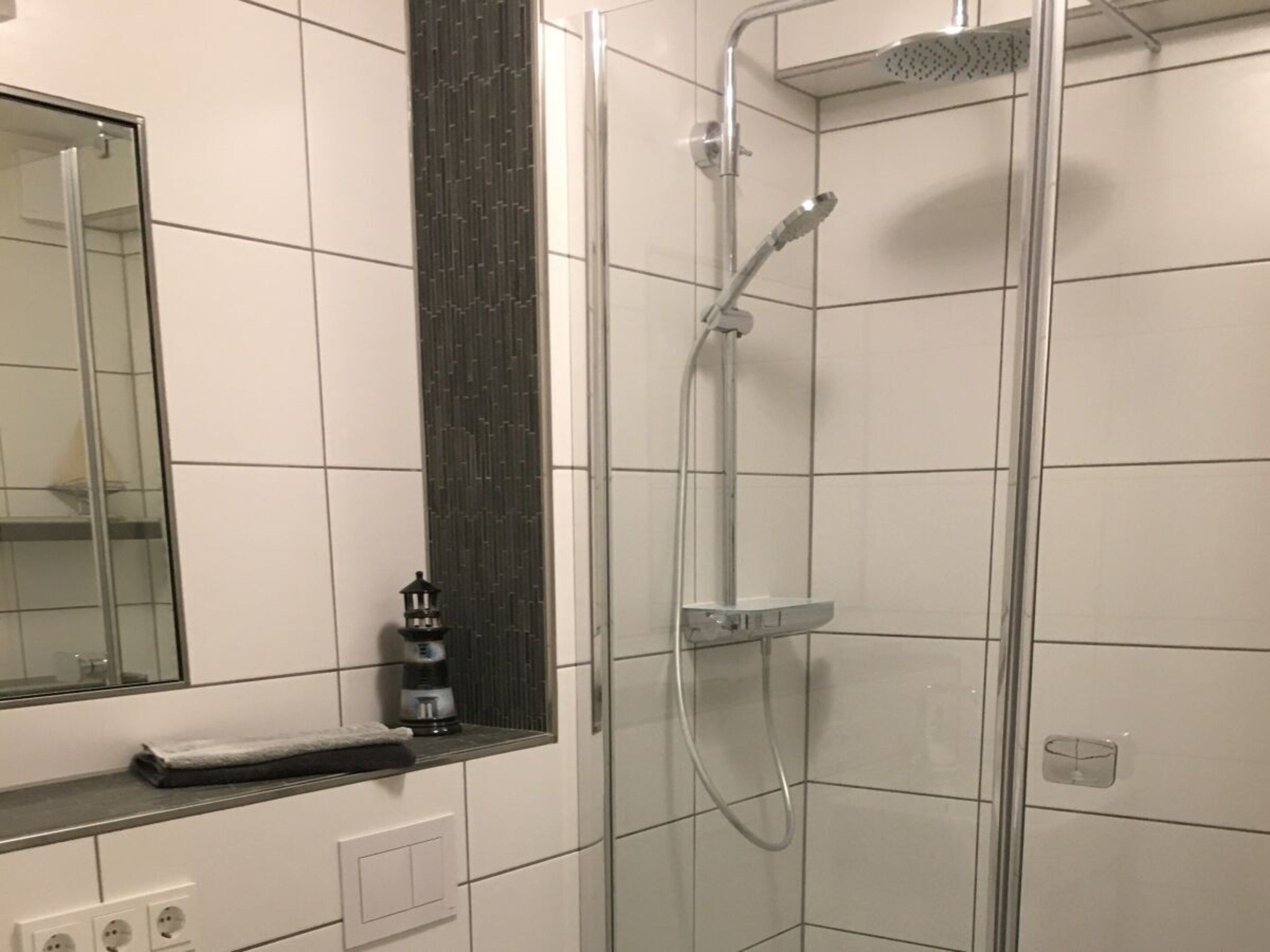 Ein Badezimmer mit Duschkabine aus Glas, Waschbecken mit Handtuch und Spiegel.
