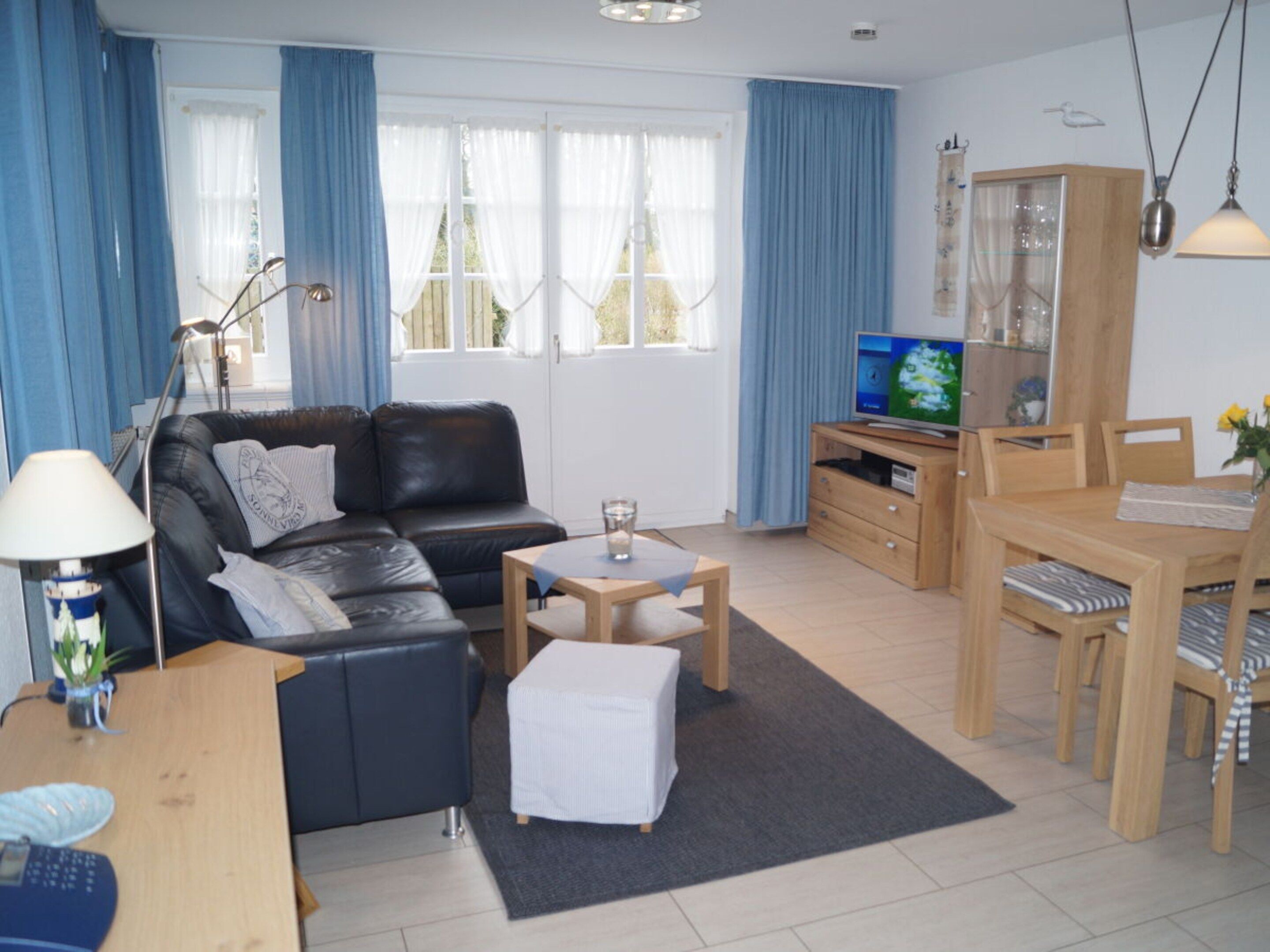 A living room with a sofa, a coffee table, a TV, and a dining area with chairs and a table.