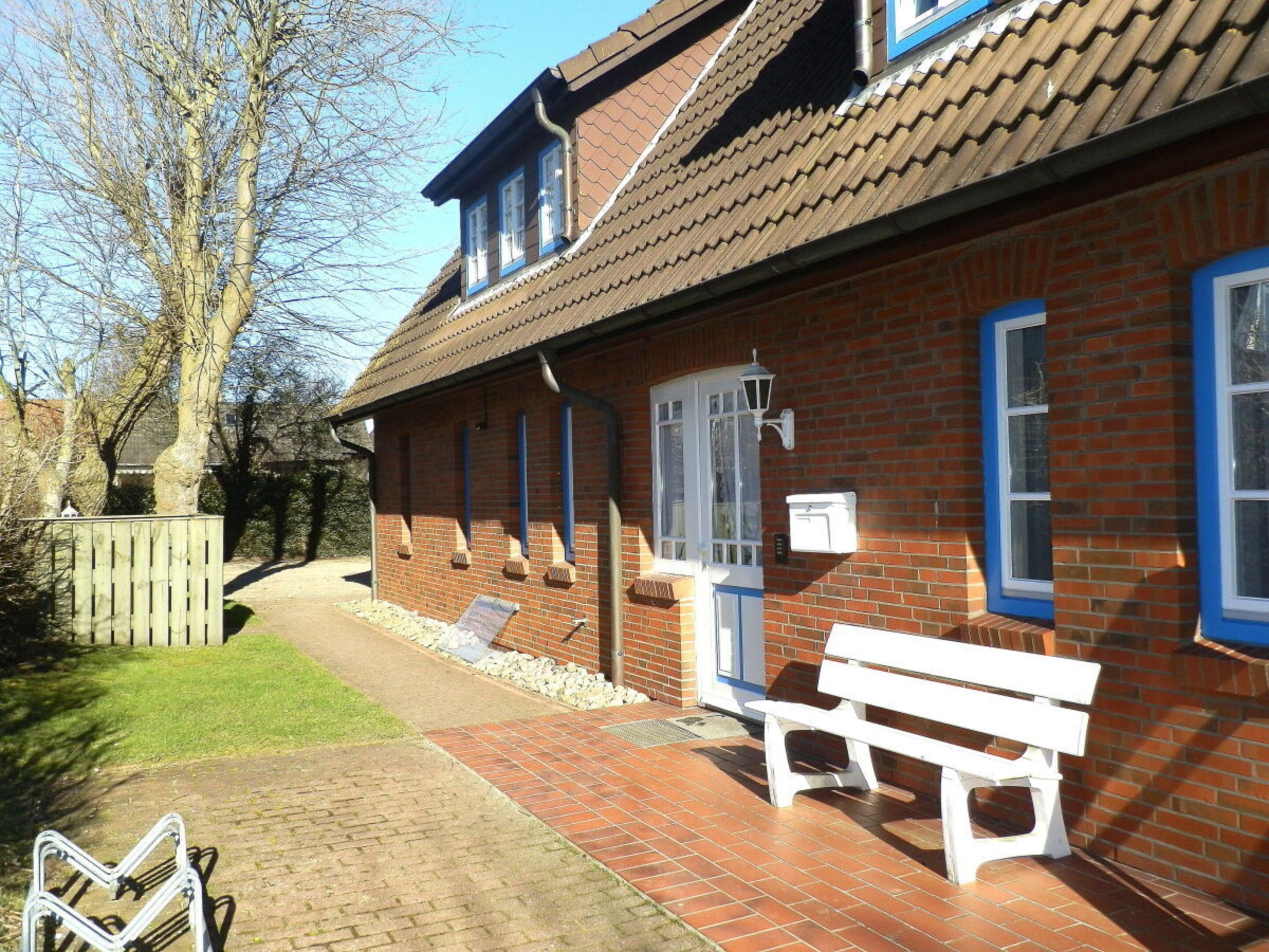 A brick building with a tiled roof, a bench, and a pathway leading to it.