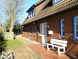 A brick building with a tiled roof, a bench, and a pathway leading to it. - Holiday Apartment With 1 Bedroom (Wyk auf Foehr)