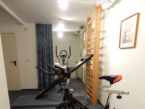 Un gimnasio en casa con una máquina elíptica, una bicicleta estática y una barra de dominadas.