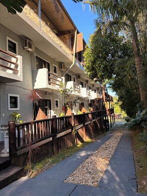Un edificio de varios pisos con balcones, una cerca de madera y un sendero.