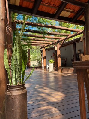 Una terraza cubierta de madera con vistas a un jardín y un edificio al fondo.