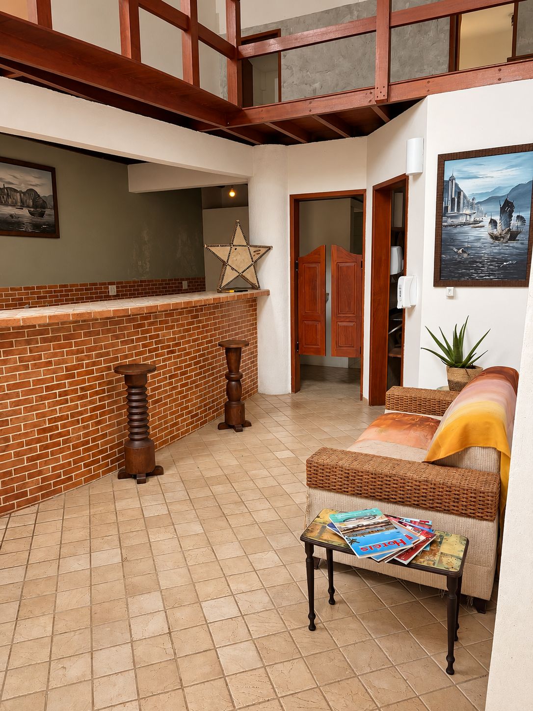 Amplia sala de estar con chimenea de ladrillo, un sofá de mimbre y una mesa de centro con revistas.