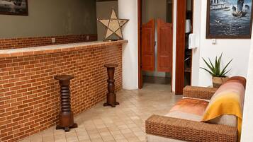 Amplia sala de estar con chimenea de ladrillo, un sofá de mimbre y una mesa de centro con revistas.