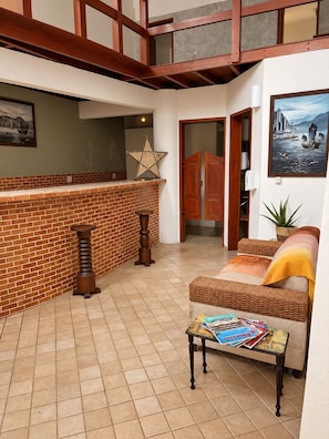 Amplia sala de estar con chimenea de ladrillo, un sofá de mimbre y una mesa de centro con revistas.