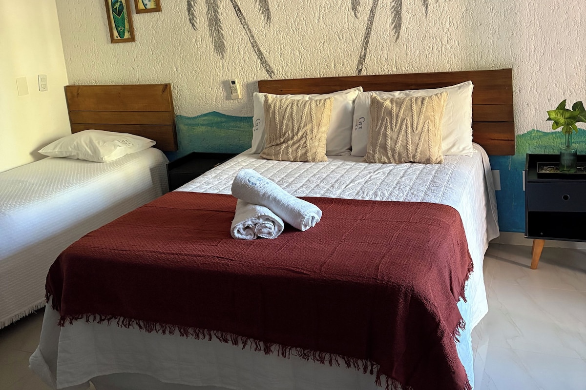 Un dormitorio con una cama, dos mesitas de noche y una pared decorada.