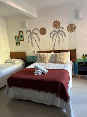 Un dormitorio con una cama, dos mesitas de noche y una pared decorada.