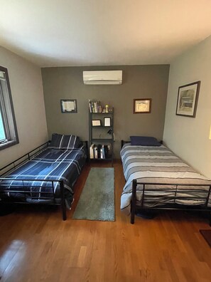 Une chambre avec deux lits, une bibliothèque et un appareil de climatisation.