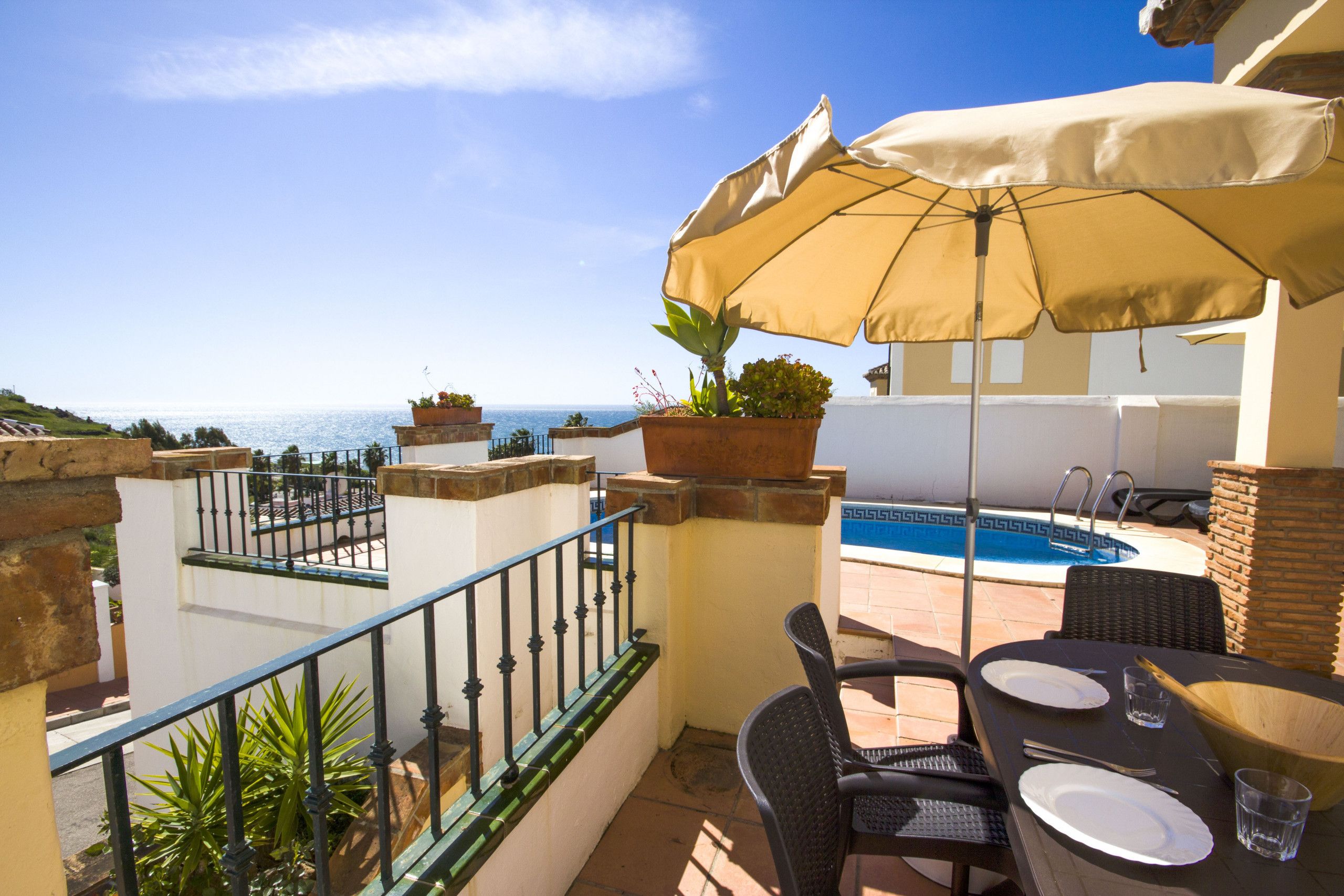 Un balcone con vista sul mare, una piscina e mobili da esterno.