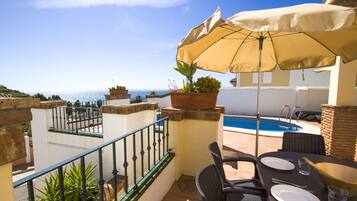 Un balcone con vista sul mare, una piscina e mobili da esterno.