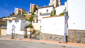 Une rue bordée de bâtiments blancs, un mur de pierre et un lampadaire.