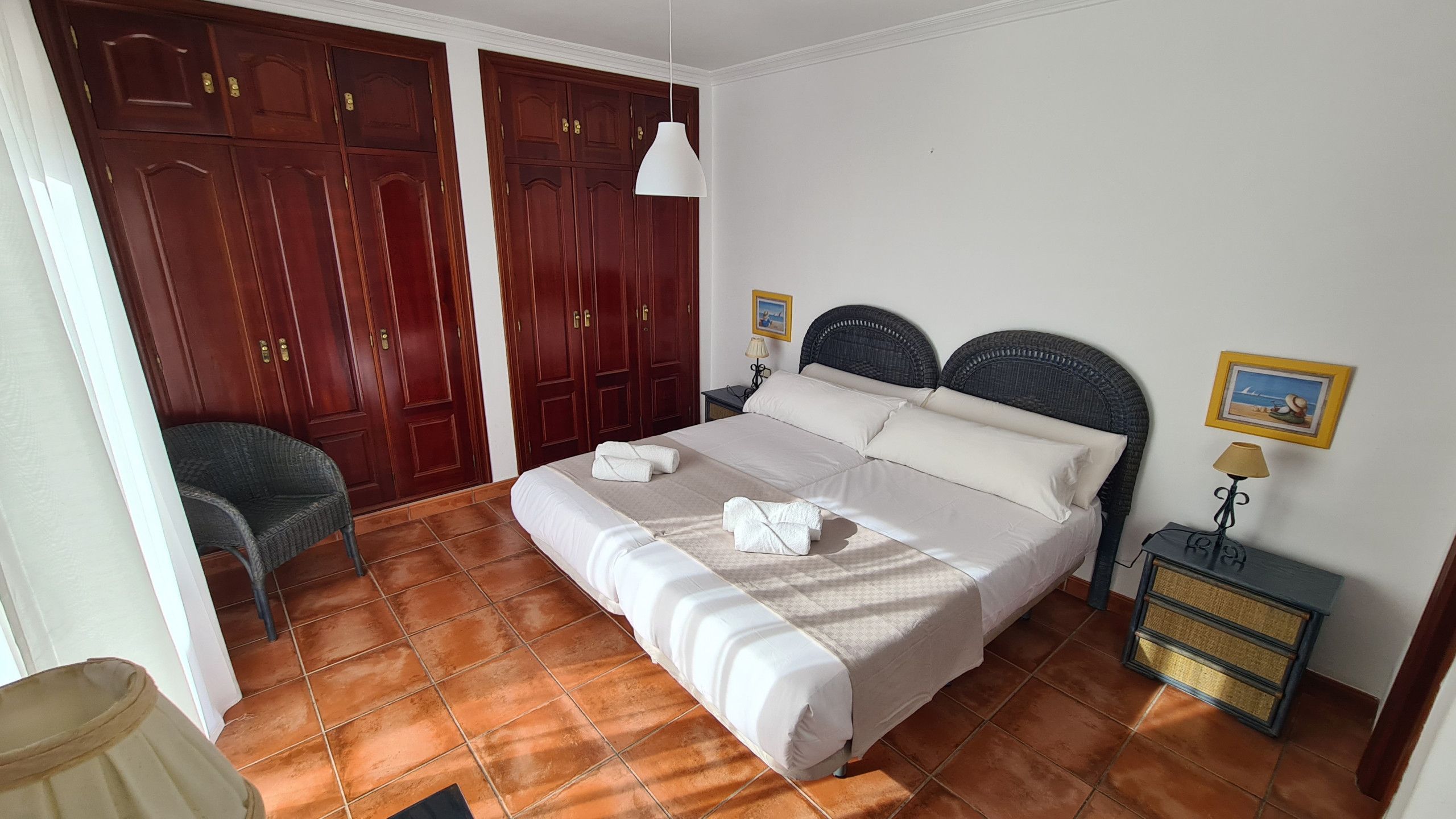 Une chambre à coucher comprenant un lit, deux tables de chevet, une chaise et une armoire.