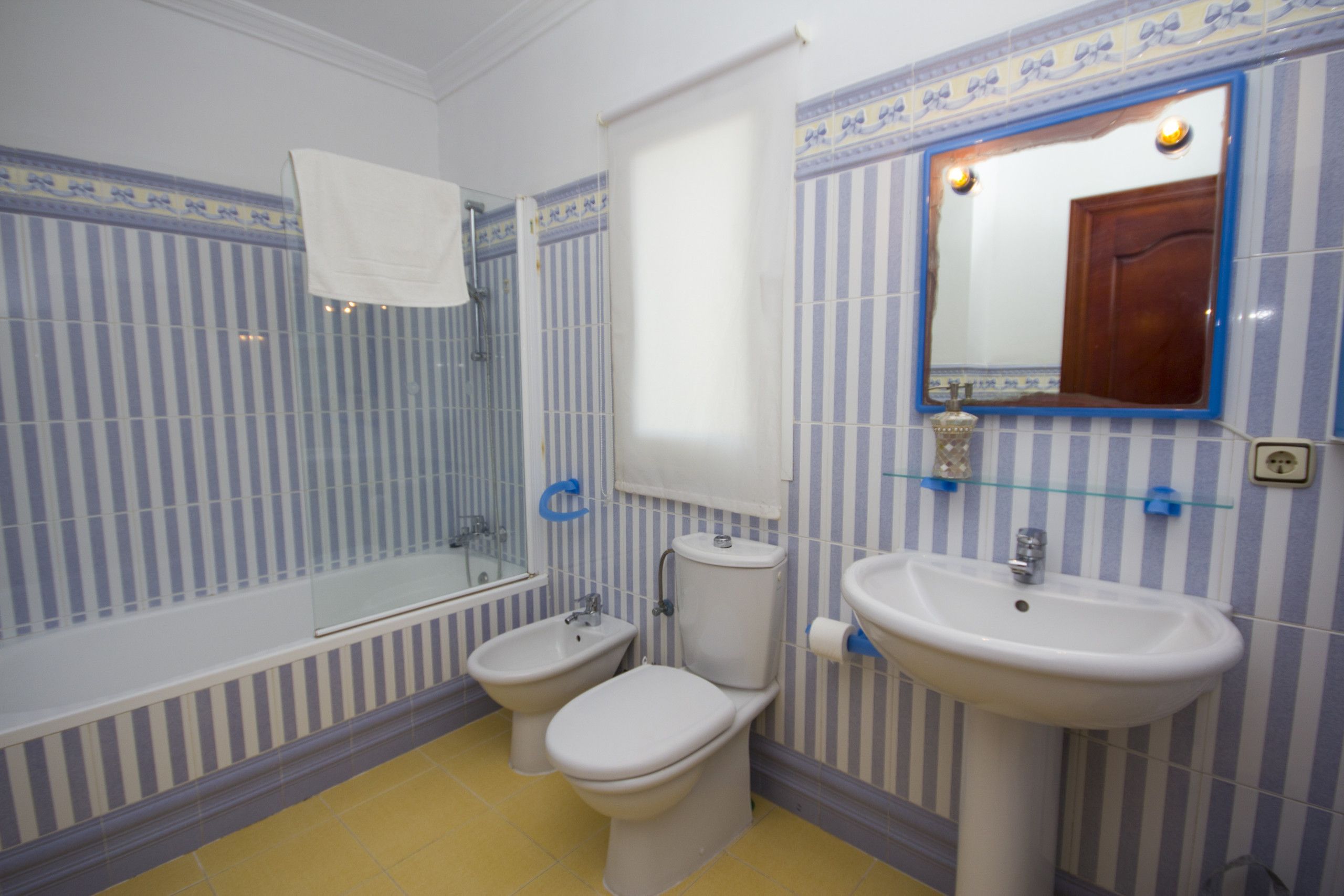 Une salle de bain avec une baignoire, deux toilettes, un lavabo et un miroir.