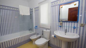 Une salle de bain avec une baignoire, deux toilettes, un lavabo et un miroir.