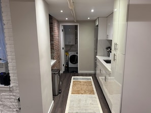 A modern kitchen with white cabinets, a built-in washing machine, and a grey countertop. - Prime West Village 3BR/2.5BA  Available Nov 9–Jan 31  30+ Night Stays (New York)