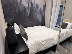 A bedroom with a bed, a bedside table, a mirror, and a wall with a forest mural. - Prime West Village 3BR/2.5BA  Available Nov 9–Jan 31  30+ Night Stays (New York)