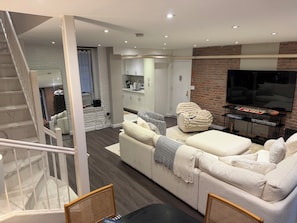 A modern living room with a sofa, a television, and a kitchen in the background. - Prime West Village 3BR/2.5BA  Available Nov 9–Jan 31  30+ Night Stays (New York)